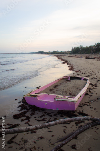 Una vecchia barca rosa abbandonata sulla spiaggia, sepolta parzialmente e piena di sabbia sulla spiaggia dell'isola di Pellestrina