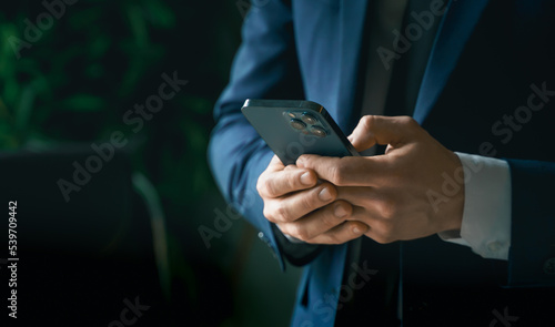 Businessman in suit with mobile phone in hands. Man typing message, using social net. Checking news. Making business meeting. Modern office.General manager,ceo.Calling to partner.Planning working day