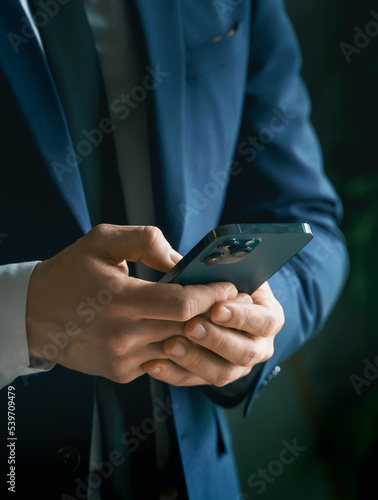 Businessman in suit with mobile phone in hands. Man typing message, using social net. Checking news. Making business meeting. Modern office.General manager,ceo.Calling to partner.Planning working day