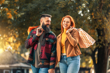 Happy couple with shopping bags in autumn park