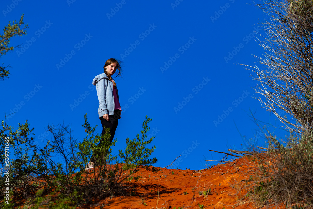 long-haired girl hiking in australian red sand desert; terra rosa in francois peron national park, shark bay, western australia long-haired girl hiking in australian red sand desert; terra rosa in francois peron national park, shark bay, western australia