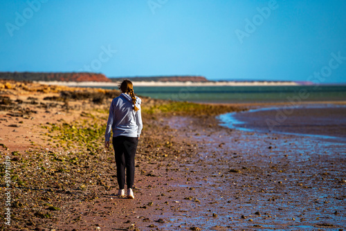 girl walks on red sand beach with red cliffs in the background, terra rosa in australia, holidays in western australia, francois peron national park