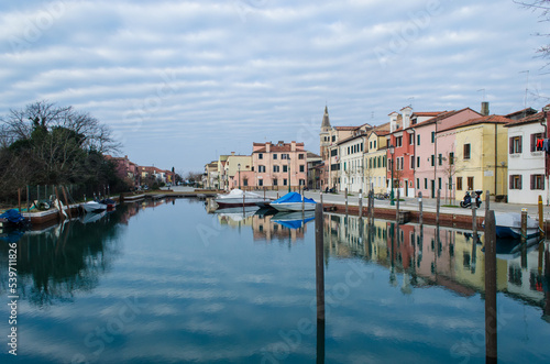 Un canale del piccolo borgo di Malamocco al Lido di Venezia in una giornata nuvolosa d'inverno con le barche ormeggiate