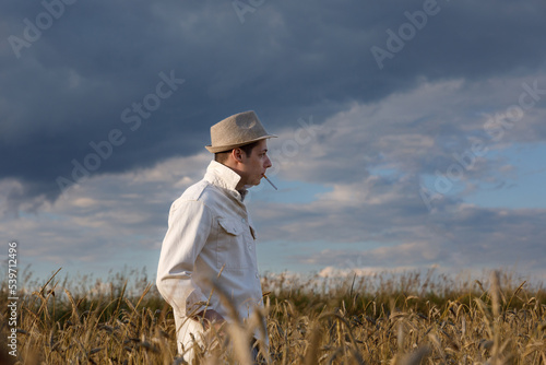 Man walks in field and smokes cigarette