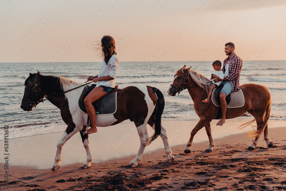 The family spends time with their children while riding horses together on a sandy beach. Selective focus The family spends time with their children while riding horses together on a sandy beach. Selective focus