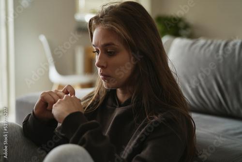 Caucasian nervous woman sitting at the couch in home