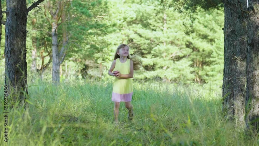 Cheerful Little Girl Hopping Runs Towards the Camera in the City Park on a Sunny Summer Day. Her Blonde Hair is Floating in the Air. The Concept of a Happy Carefree Childhood Cheerful Little Girl Hopping Runs Towards the Camera in the City Park on a Sunny Summer Day. Her Blonde Hair is Floating in the Air. The Concept of a Happy Carefree Childhood