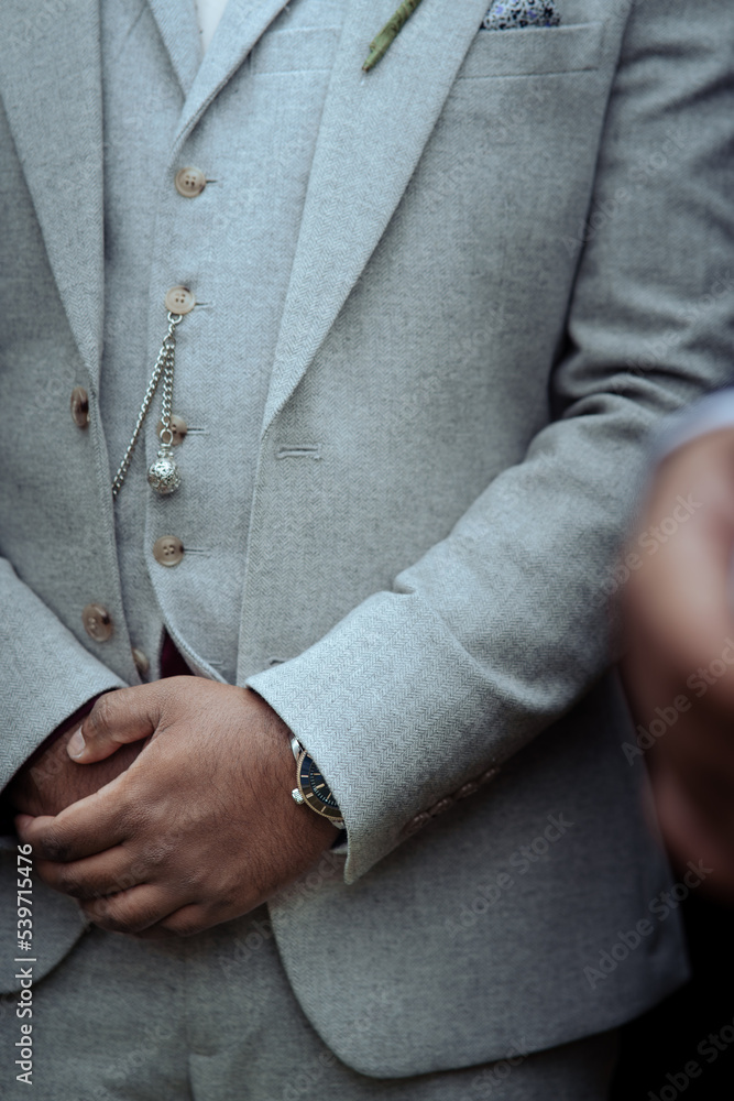 Bridegroom with arms folded in grey wedding suit