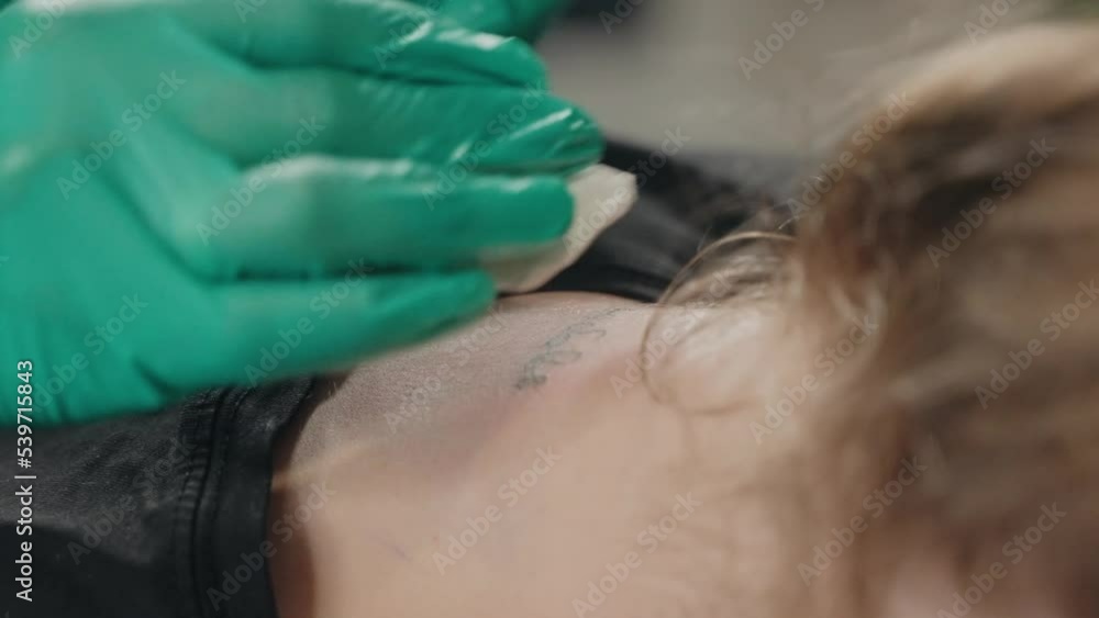 In neck of client master makes tattoo with inscription using tattoo machine. In neck of client master makes tattoo with inscription using tattoo machine.