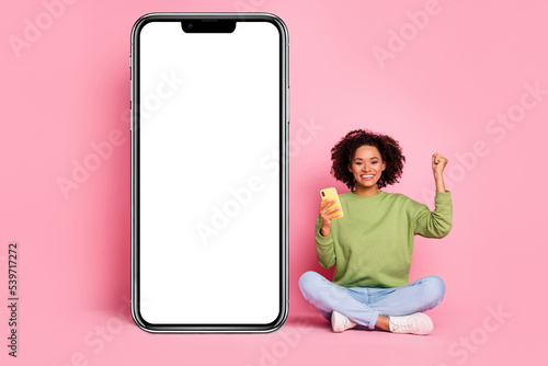 Full body photo of young pretty girl sit floor use mobile celebrate luck triumph fists hand isolated over pink color background