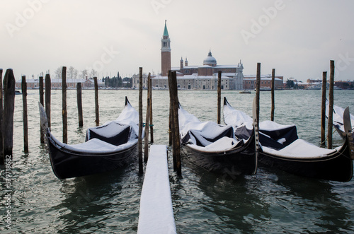 Le gondole ormeggiate nel bacino di San Marco  a Venezia, coperte dalla neve in una giornata invernale photo