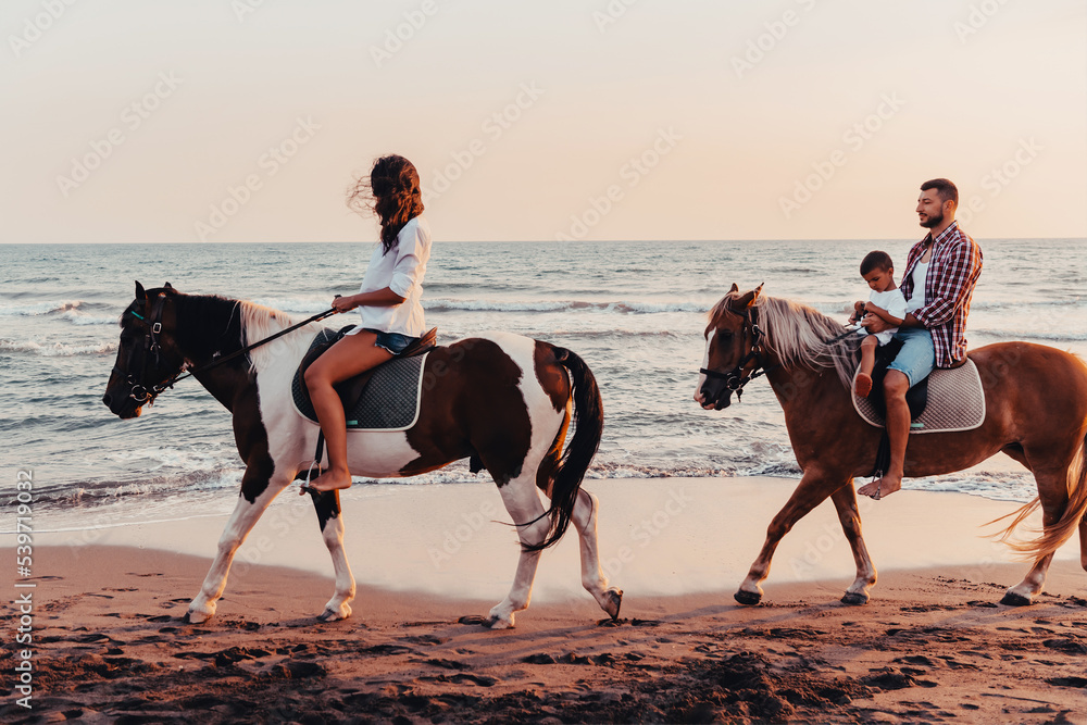 The family spends time with their children while riding horses together on a sandy beach. Selective focus The family spends time with their children while riding horses together on a sandy beach. Selective focus