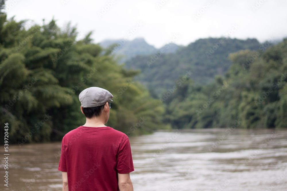 The man standing backward and watching River in a Thai tourist attraction country landscape. The man standing backward and watching River in a Thai tourist attraction country landscape.
