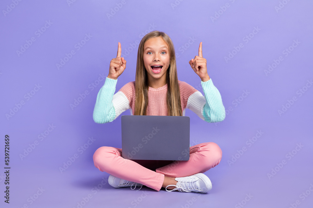 Photo of overjoyed little girl pupil hand show direct empty space online lesson use netbook gadget isolated on purple color background Photo of overjoyed little girl pupil hand show direct empty space online lesson use netbook gadget isolated on purple color background