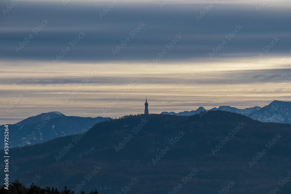 Panoramic scenic view of the viewing tower Pyramidenkogel and the snow capped Karawanks mountain range near Techelsberg, Carinthia (Kaernten), Austria, Europe. Winter wonderland in the Alps