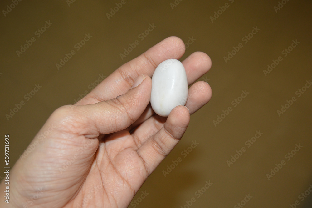 A person holding a Healing Stone, Reiki Crystal, and White Pebble in Hand. Person's hands holding crystals. A person holding a Healing Stone, Reiki Crystal, and White Pebble in Hand. Person's hands holding crystals.