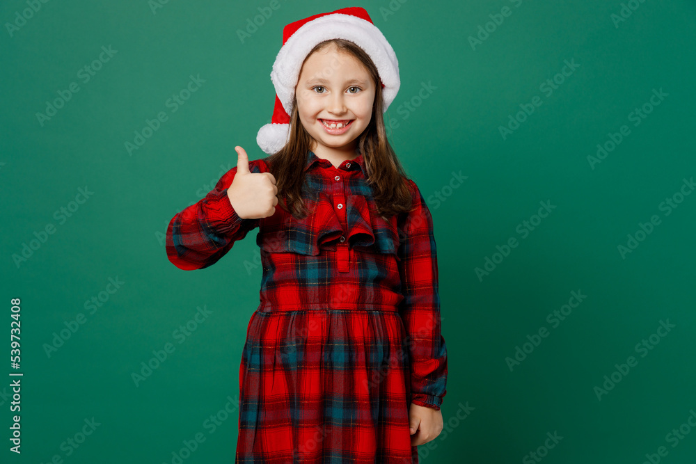 Merry smiling happy satisfied little child kid girl 6-7 years old wear red dress Christmas hat posing showing thumb up like gesture isolated on plain dark green background Happy New Year 2023 concept Merry smiling happy satisfied little child kid girl 6-7 years old wear red dress Christmas hat posing showing thumb up like gesture isolated on plain dark green background Happy New Year 2023 concept