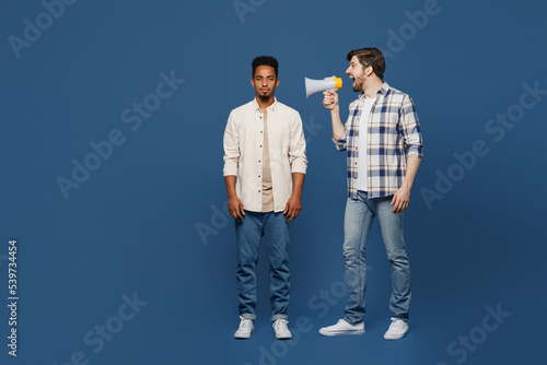 Full body side view young two friends men wear white casual shirts together hold scream to carefree guy in megaphone announces discounts sale Hurry up isolated plain dark royal navy blue background. photo