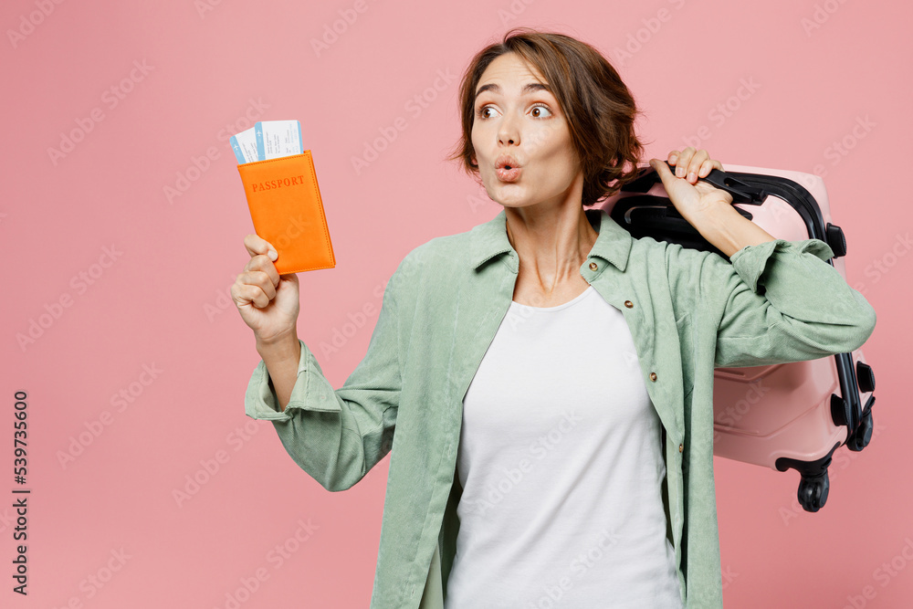 Traveler amazed woman wear green shirt hold suitcase passport ticket isolated on plain pastel light pink background. Tourist travel abroad in free time rest getaway. Air flight trip journey concept. Traveler amazed woman wear green shirt hold suitcase passport ticket isolated on plain pastel light pink background. Tourist travel abroad in free time rest getaway. Air flight trip journey concept.