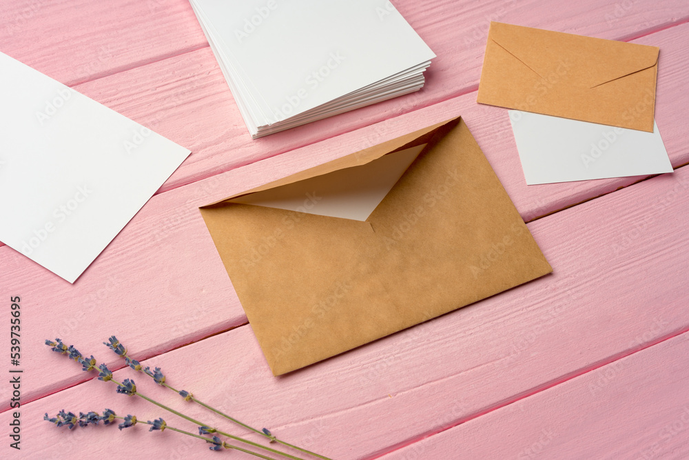 Beige envelope with blank letter on pink wooden desk Beige envelope with blank letter on pink wooden desk