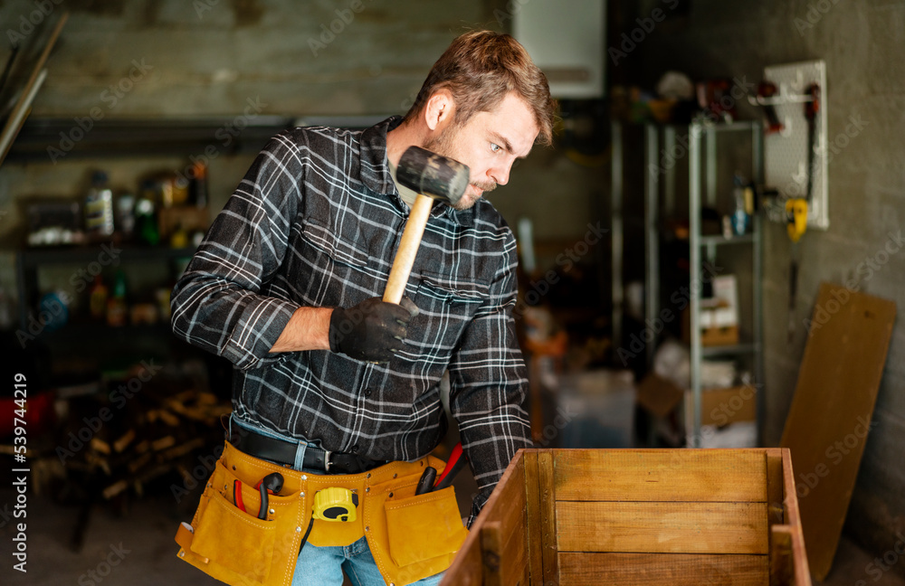 Handyman adult man using a hummer while working in workshop. Handyman adult man using a hummer while working in workshop.
