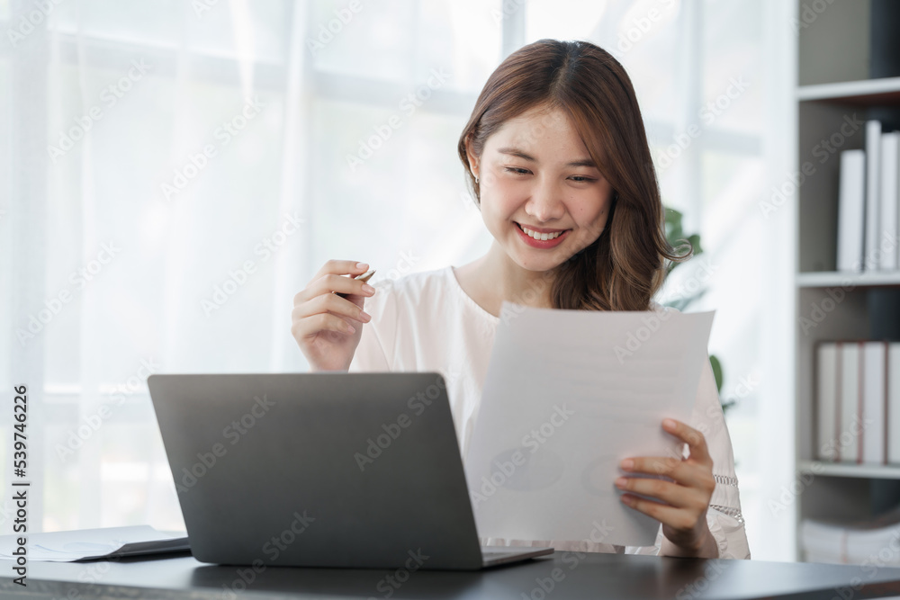 Smile Pretty business Asian woman freelancer is working her job on a laptop computer in a modern office. Doing accounting analysis report real estate investment data, Financial and tax systems concept Smile Pretty business Asian woman freelancer is working her job on a laptop computer in a modern office. Doing accounting analysis report real estate investment data, Financial and tax systems concept