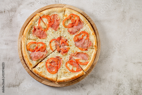 Fresh tasty pizza with meat, sausages, salamy and ham on white concrete background