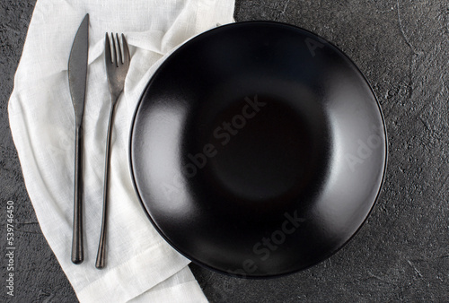 Empty ceramic plate, linen napkin on a dark stone background Copy space Top view