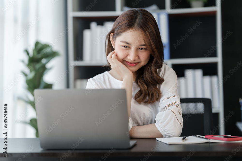 Smile Pretty business Asian woman freelancer is working her job on a laptop computer in a modern office. Doing accounting analysis report real estate investment data, Financial and tax systems concept Smile Pretty business Asian woman freelancer is working her job on a laptop computer in a modern office. Doing accounting analysis report real estate investment data, Financial and tax systems concept