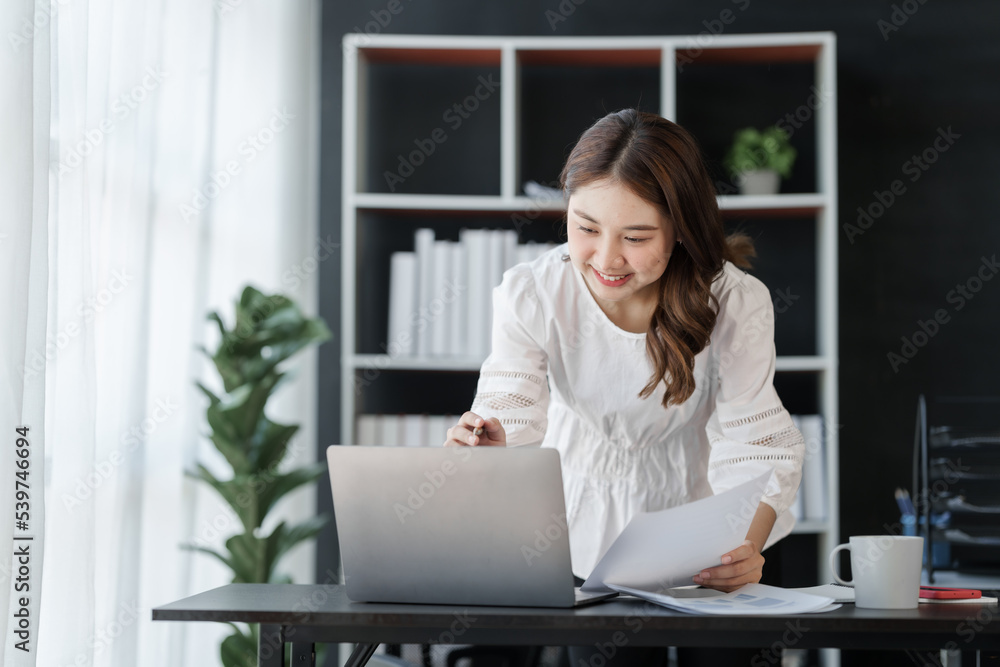 Smile Pretty business Asian woman freelancer is working her job on a laptop computer in a modern office. Doing accounting analysis report real estate investment data, Financial and tax systems concept