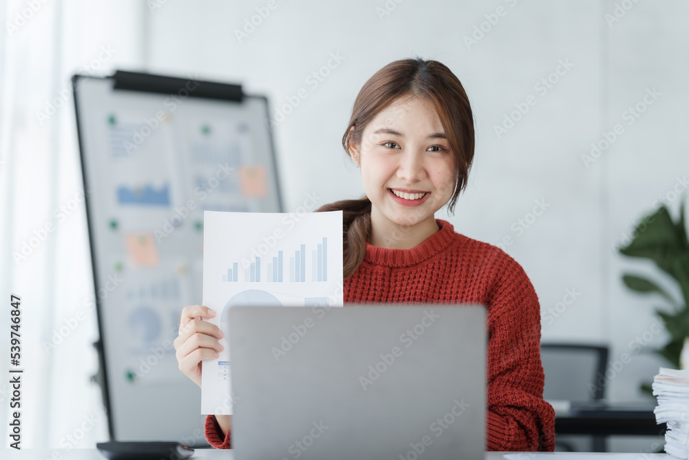 Confident Asian female office worker freelancer working in office, wearing red sweater, thai people.