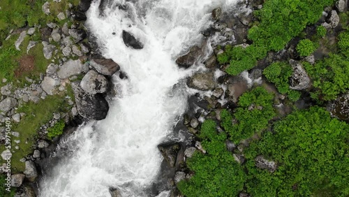 River, top view. Water stream running through stone boulders river in a green valley. Wild mountain river water splashing in summer day