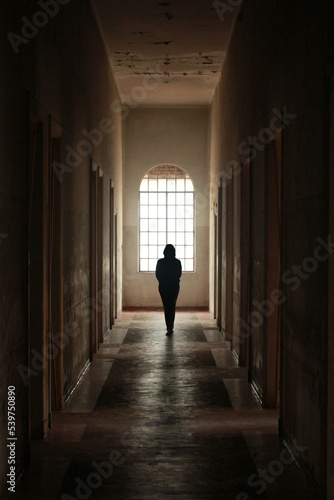View of a dark creepy dark hall with a woman in the center