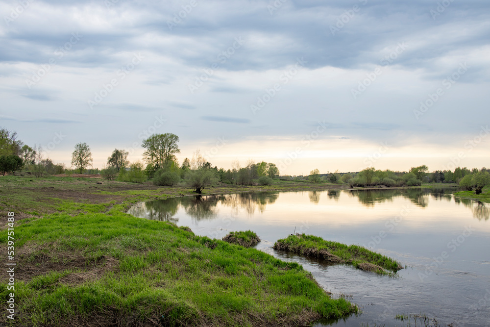 Spring landscape, dramatic sky over the river. View of the river in the evening.