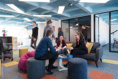 Multiethnic startup business team on meeting in a modern bright open space coworking office. Brainstorming, working on laptop. Group of coworkers walking around in motion blur. 