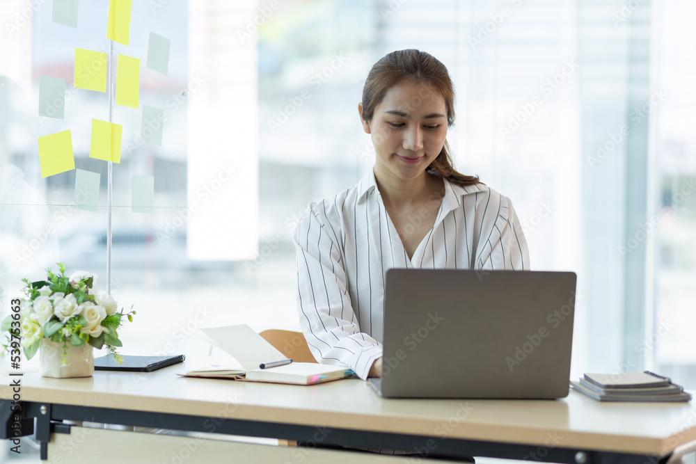 Charming Asian businesswoman working on a laptop in the office. Charming Asian businesswoman working on a laptop in the office.