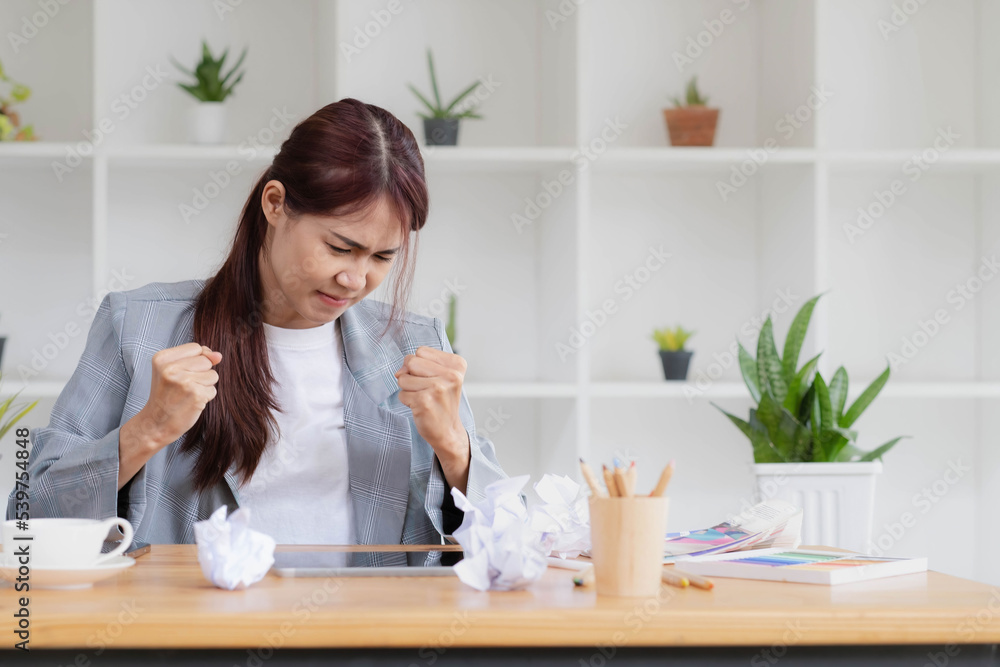 Mad Angry Stressed young asian female graphic designer or businesswoman with a crumpling paper on the table dissatisfied with her work, complained from her boss, getting a job problem. Mad Angry Stressed young asian female graphic designer or businesswoman with a crumpling paper on the table dissatisfied with her work, complained from her boss, getting a job problem.