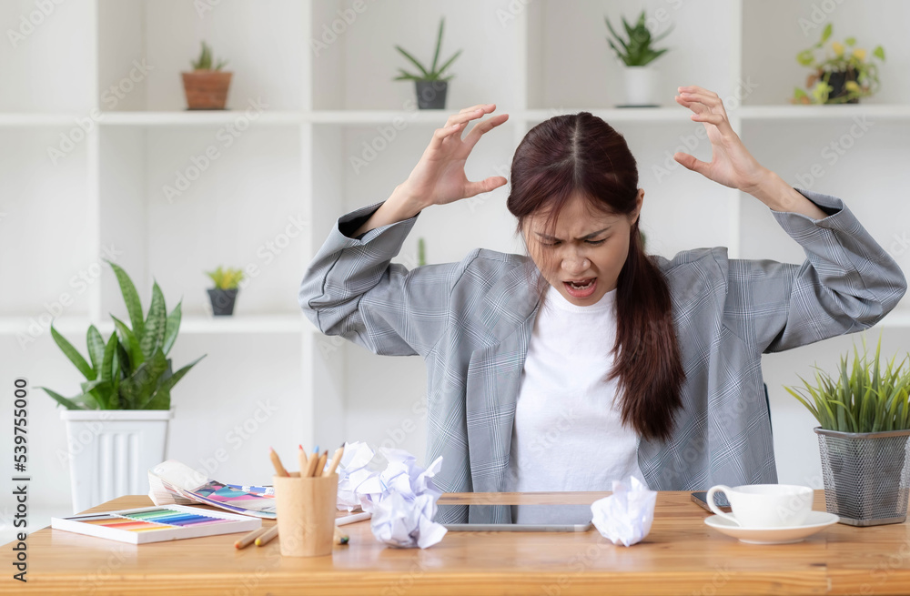 Mad Angry Stressed young asian female graphic designer or businesswoman with a crumpling paper on the table dissatisfied with her work, complained from her boss, getting a job problem. Mad Angry Stressed young asian female graphic designer or businesswoman with a crumpling paper on the table dissatisfied with her work, complained from her boss, getting a job problem.