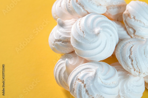 "Suspiros" or meringue, sweet made with egg whites, sugar and a few drops of lemon on a yellow background.