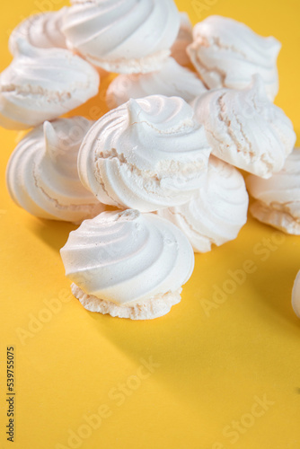 "Suspiros" or meringue, sweet made with egg whites, sugar and a few drops of lemon on a yellow background.