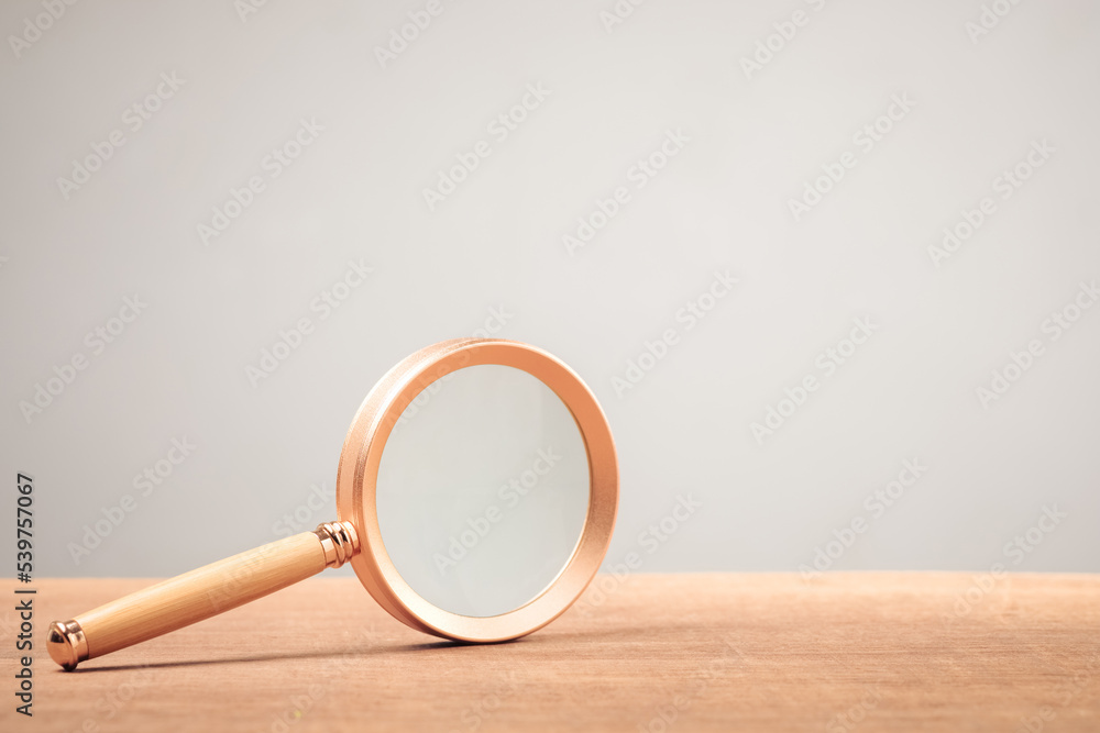 Magnifying glass on wood table and clean wall as copy space Stock Photo