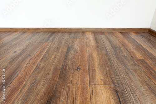 Laminated wood floor with white wall. Empty room with floating laminate in new apartmen © dechevm