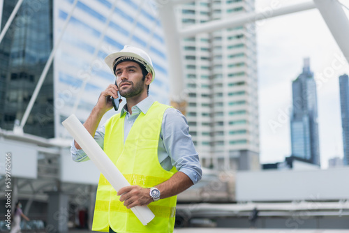 Man engineer standing on construction site. construction manager using walkie talkie. Engineer working on outdoor project and talking on phone