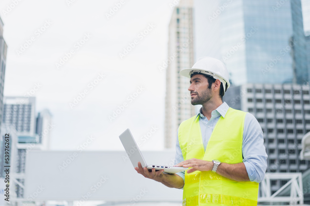Man engineer standing on construction site. construction manager using walkie talkie. Engineer working on outdoor project and control with laptop