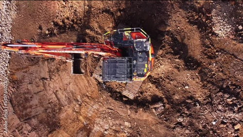 Excavator filling bucket with semi-dry concrete on construction site Excavator filling bucket with semi-dry concrete on construction site Aerial shot	 photo