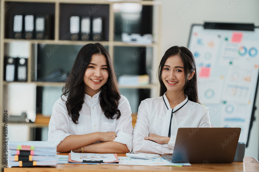 Portrait of beautiful asian businesswoman holding cup of coffee, smiling and looking at camera while sitting at office desk. Portrait of beautiful asian businesswoman holding cup of coffee, smiling and looking at camera while sitting at office desk.
