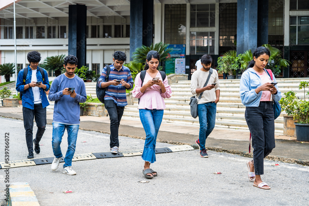 Fototapeta premium group of students busy checking result or using on mobile phone at college campus - concept of social media, smartphone addiction and technology.
