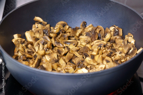 Fried mushrooms and eggs in a pan. The process of cooking breakfast. Close up. Selective focus