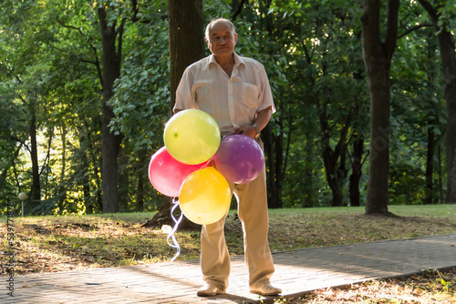 An old man is playing in the park with bright, balloons on his birthday. photo