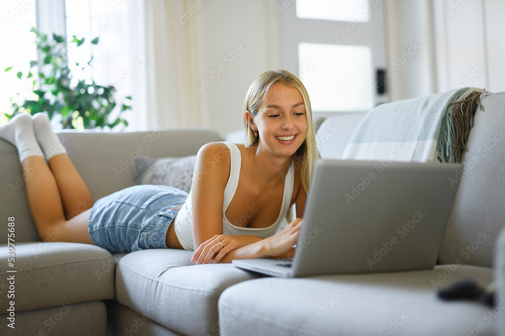 Happy teenager girl online with a laptop in the living room at home Happy teenager girl online with a laptop in the living room at home